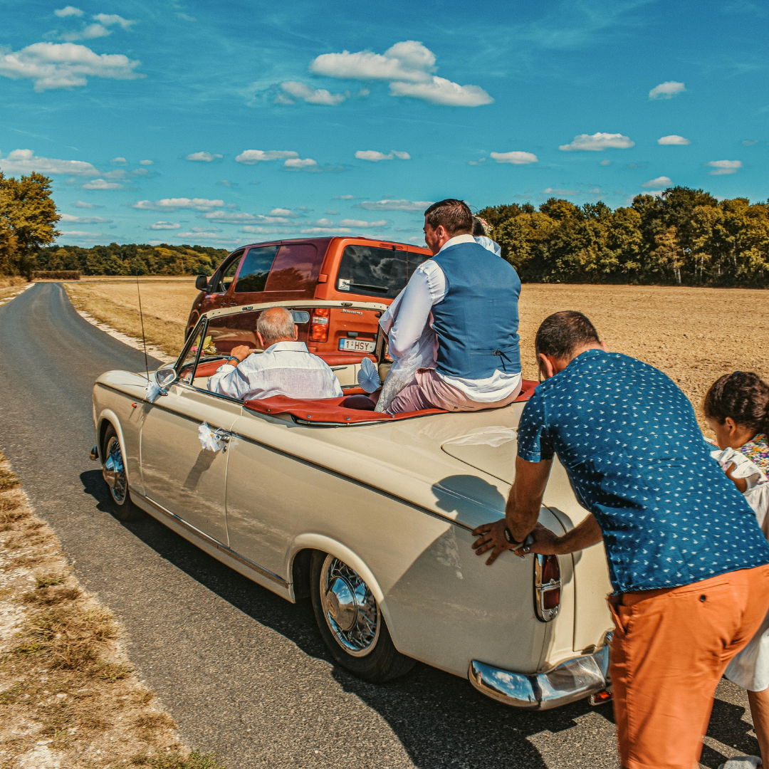 dad and his daughter push starting a old classic wedding car