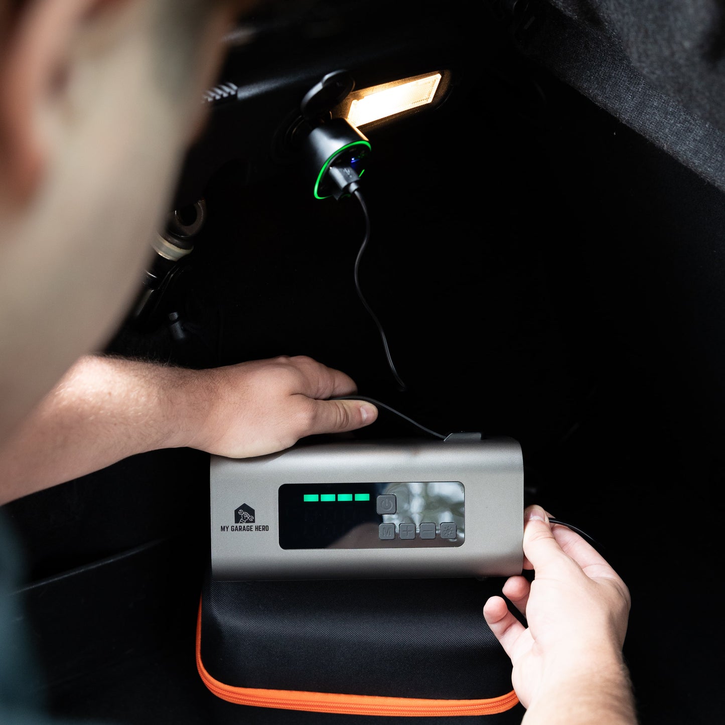 portable jump starter and tyre inflator being charged with a usb-c cord in a cars 5 volt cigarette port with the Bluetooth usb car charger.
