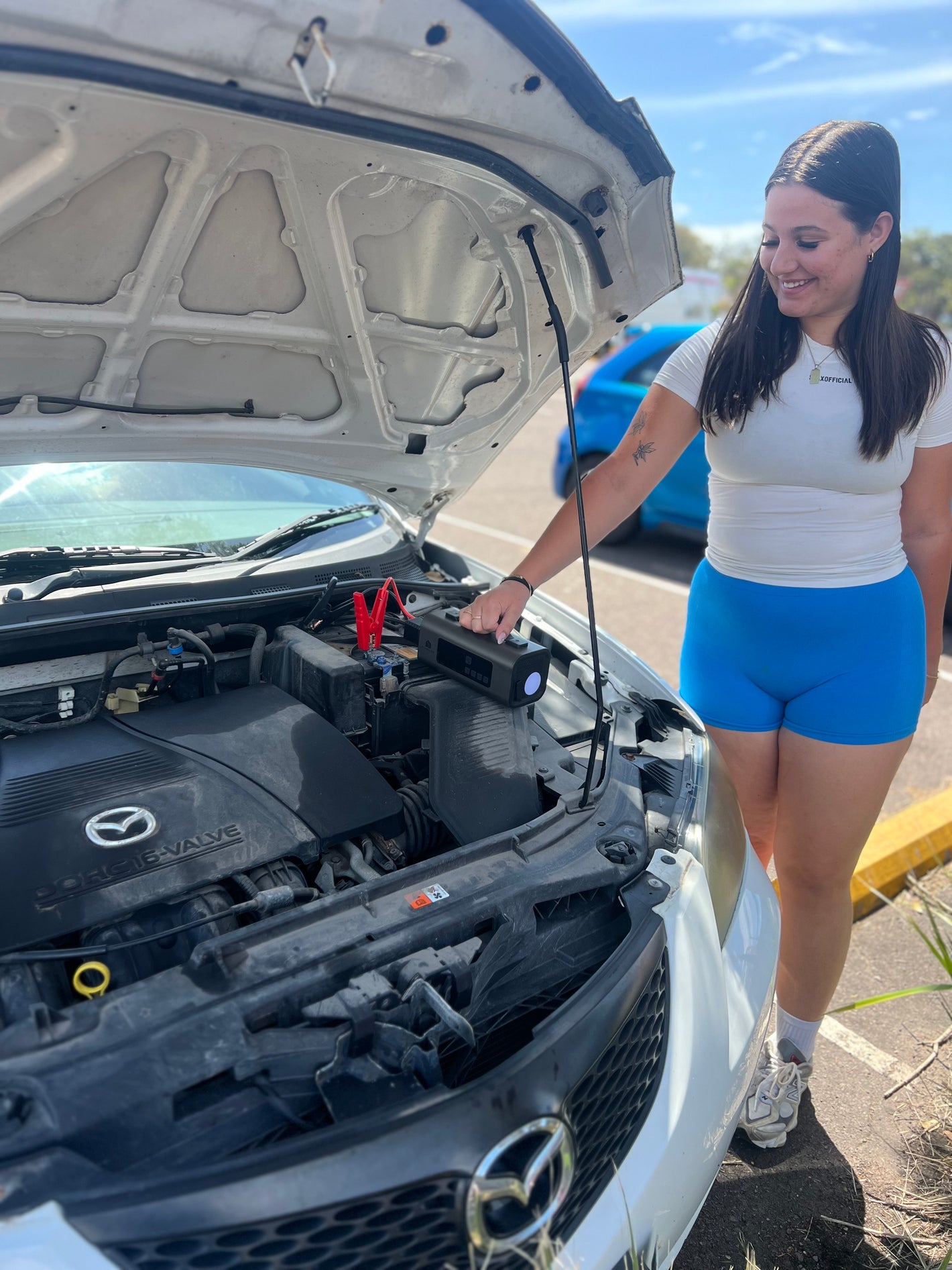 picture of girl next to car happily using a portable jump starter and tyre inflator