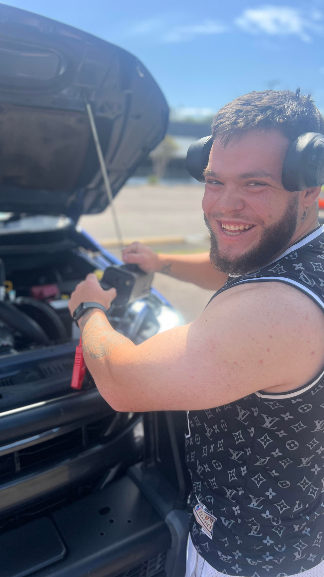 happy customer smiling while plugging in his jump start cables into his portable jump starter and tyre inflator