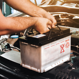 lead acid battery being lifted into a car engine 