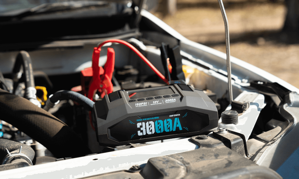 Car jump starter device in a car's open hood with visible battery connections.
