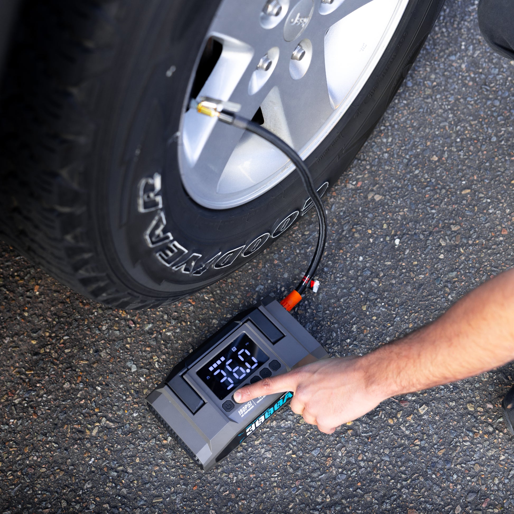 Close-up of the Boost N’ Inflate Pro inflating a car tyre on the road, with a person adjusting the digital controls during real-world use.