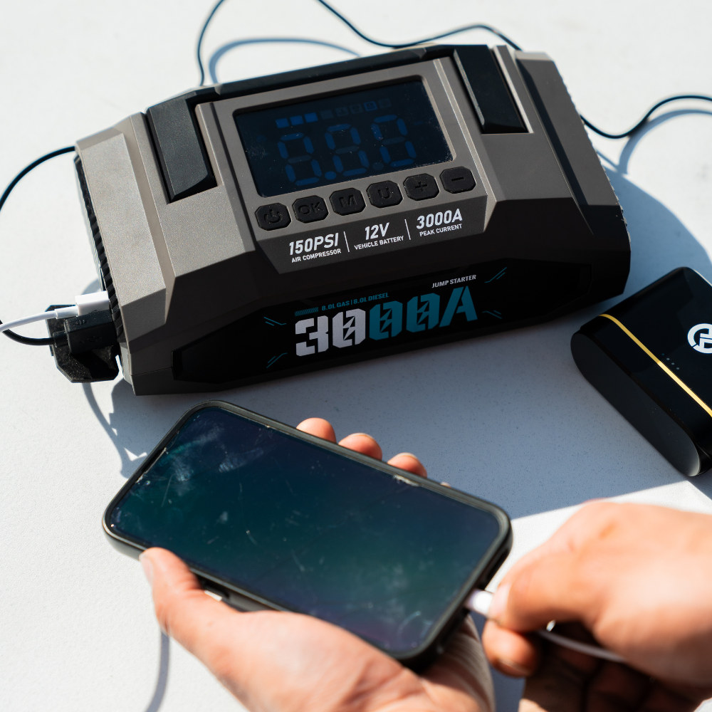 Boost N’ Inflate Pro charging a smartphone via USB, showing the unit’s 3000A power bank functionality with the digital display and ports clearly visible.