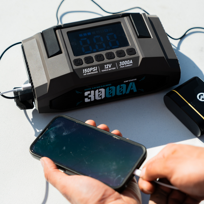 Boost N’ Inflate Pro charging a smartphone via USB, showing the unit’s 3000A power bank functionality with the digital display and ports clearly visible.