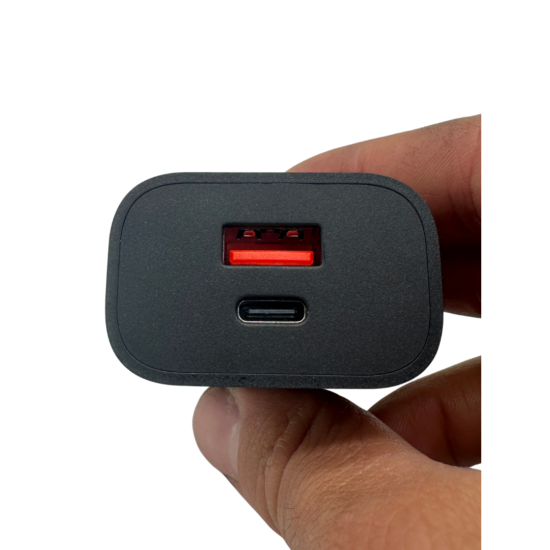 Close-up of a black wall charger adapter showing USB-A and USB-C ports, held in a hand against a white background