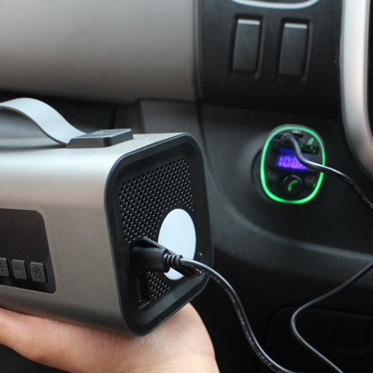 Bluetooth car charger plugged into a vehicle’s 12V socket while charging a device from the rear USB port. LED display and green lighting ring visible on the charger during in-car use.