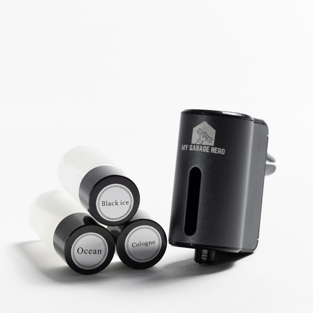 Car Diffuser – Premium Fragrance displayed in a white studio setup with three fragrance refill bottles labeled Black Ice, Ocean, and Cologne stacked beside the diffuser unit at an angle.