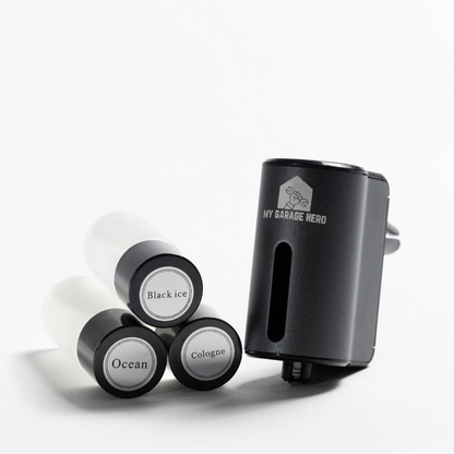 Car Diffuser – Premium Fragrance displayed in a white studio setup with three fragrance refill bottles labeled Black Ice, Ocean, and Cologne stacked beside the diffuser unit at an angle.