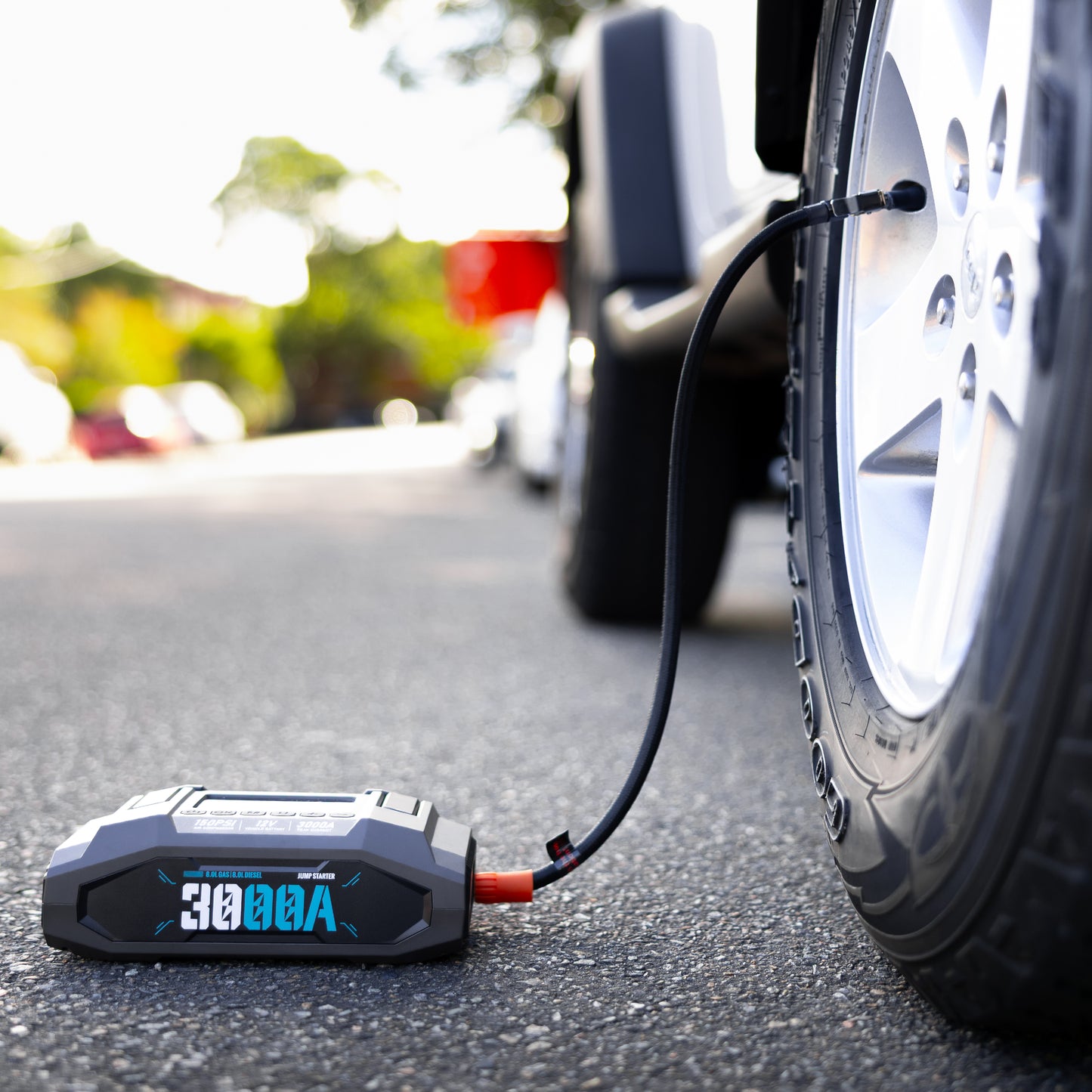Boost N’ Inflate Pro by My Garage Hero inflating a car tyre on the side of the road, showing the 3000A jump starter and portable air compressor connected to the tyre valve.