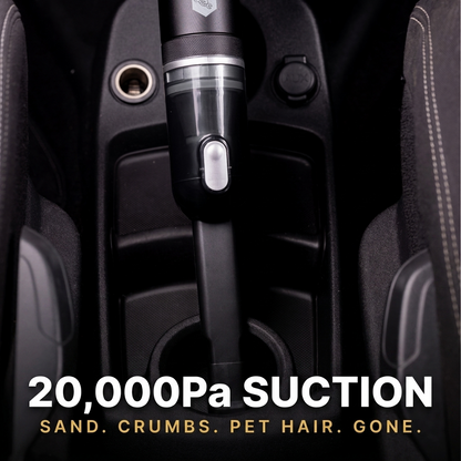 A handheld black car vacuum cleaner shown upright in a car center console, with large text reading '20,000Pa SUCTION' and smaller text 'SAND. CRUMBS.